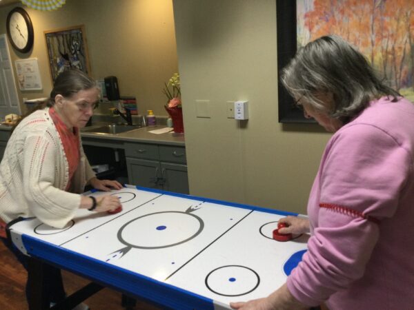 two elderly women playing air hockey