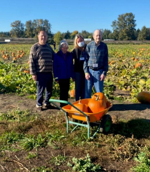 life enrichment activity at the pumpkin patch with residents holding pumpkins in a field
